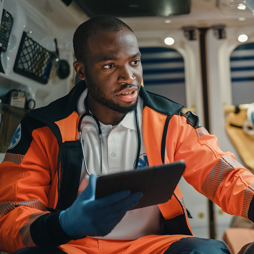 EMT talking to patient in ambulance while holding a smart tablet